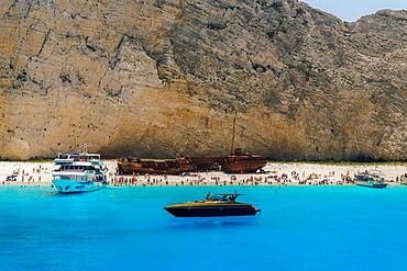 Shipwreck on Navagio Beach, a famous beach with crystal clear waters, moored leisure boats and bathers, Zakynthos, Ionian Islands, Greek Islands, Greece, Europe