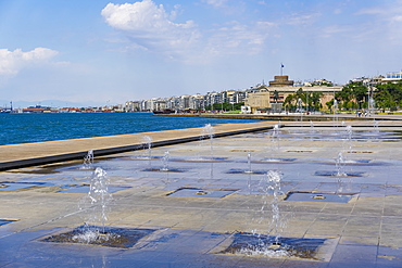 Waterfront view of fountains at umbrellas area, statue of Alexander The Great and city's landmark White Tower, Thessaloniki, Greece, Europe