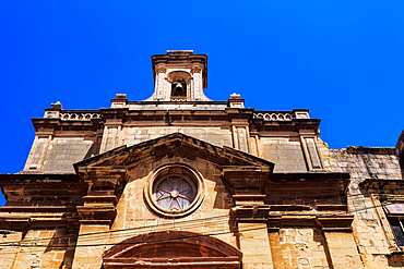 Malta Oratory of The Holy Cross exterior with limestone, Maltese cross and bell tower under a bright blue sky, old city of Birgu (Citta Vittoriosa), Malta, Mediterranean, Europe