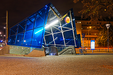 A modern design illuminated empty metro stop entrance with logo at night in Warsaw, Poland, Europe