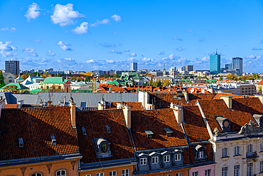 Panoramic view of city skyline with traditional low-rise roof-tiled houses and modern skyscrapers under a blue sky with clouds, Warsaw, Poland, Europe