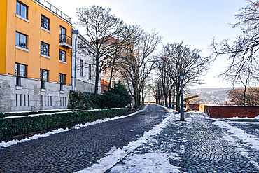 Buda Castle with buildings next to cobblestone pathway in winter with melting snow around, Budapest, Hungary, Europe