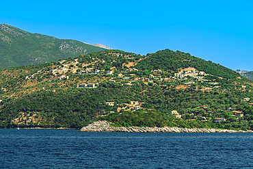 Sea view of low rise houses on the hill and close to the beach surrounded by green forest, Lefkada, Ionian Island, Greek Islands, Greece, Europe