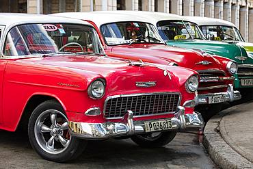 Red and green vintage American cars parked in a taxi rank near the train station, Havana, Cuba, West Indies, Caribbean