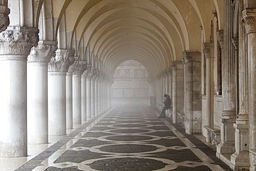 Misty view of pillars with lone woman sitting, Doge's Palace, St. Mark's Square, Venice, UNESCO World Heritage Site, Veneto, Italy, Europe