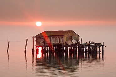 Old fishermen's shack at sunset in Venetian lagoon off the coast of Pellestrina, Venice, Veneto, Italy, Europe