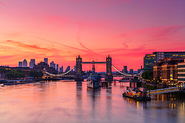 Tower Bridge, River Thames and HMS Belfast at sunrise with pink sky, and Canary Wharf in background, London, England, United Kingdom, Europe