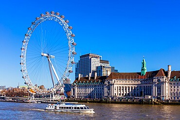 A boat passing in front of the London Eye and London Aquarium on a sunny day, London, England, United Kingdom, Europe