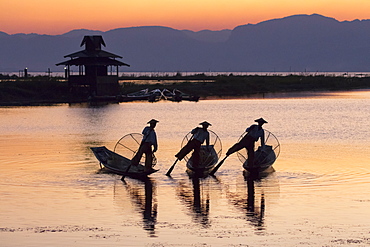 Three fishermen balance on one leg at sunset on Inle Lake, Shan State, Myanmar (Burma), Asia