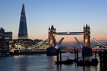 Tower Bridge illuminated at night, with the bridge raised over the River Thames, London, England, United Kingdom, Europe