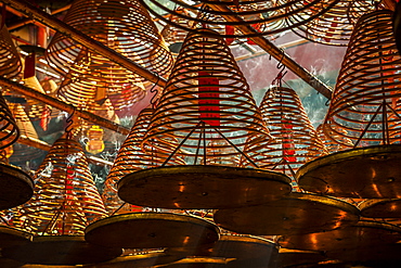 Beams of light streaming into Man Mo Temple past the large incense coils hanging from the ceiling of the Temple, Hong Kong, China, Asia