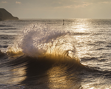 Waves backlit by the dawn sun reflect off the sea wall and impact with an incoming one, Exmouth, Devon, England, United Kingdom, Europe