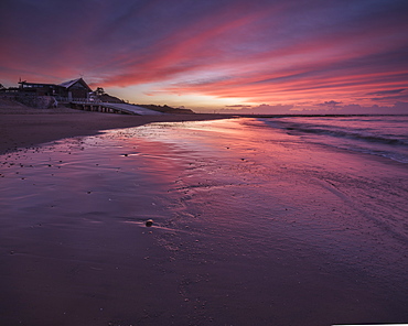 Vibrant dawn sky with the RNLI Station reflected in the wet beach, Exmouth, Devon, England, United Kingdom, Europe