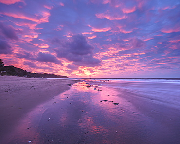 Intensely coloured and mirrored dawn sky looking towards Orcombe Point, Exmouth, Devon, England, United Kingdom, Europe