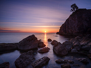 A colourful sunrise over Torbay with warm light on rocks, Babbacombe, Torquay, Devon, England, United Kingdom, Europe