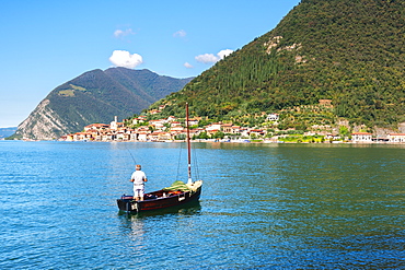 Fisherman with a view of Peschiera Maraglio, Monte Isola, the largest lake island in Europe, Province of Brescia, Italy, Europe