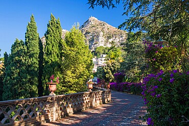 View along footpath in the gardens of the Villa Comunale, Saracen castle visible on hilltop, Taormina, Messina, Sicily, Italy, Mediterranean, Europe