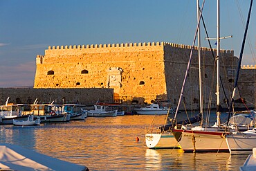 View across the Venetian Harbour, sunset, the Koules Fortress reflected in water, Iraklio (Heraklion), Crete, Greek Islands, Greece, Europe