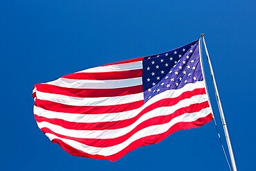 Giant US flag flying beneath a deep blue sky above Truman Avenue, Old Town, Key West, Florida Keys, Florida, United States of America, North America