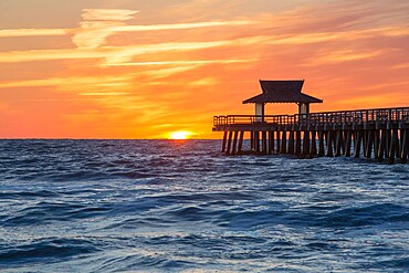 View across the Gulf of Mexico from beach beside Naples Pier, sunset, golden sky above horizon, Naples, Florida, United States of America, North America