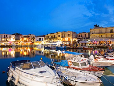 View across the Venetian Harbour at dusk, brightly lit restaurants reflected in water, Rethymno (Rethymnon), Crete, Greek Islands, Greece, Europe