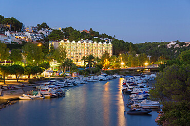 View inland along the Algendar River at dusk, bright lights reflected in water, Cala Galdana, Menorca, Balearic Islands, Spain, Mediterranean, Europe