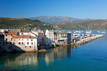 View over rooftops from the citadel ramparts, waterside houses reflected in calm sea, St-Florent, Haute-Corse, Corsica, France, Mediterranean, Europe