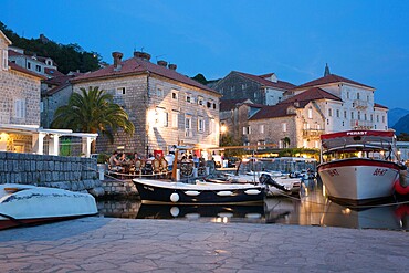 View across the illuminated harbour to waterfont mansions overlooking the Bay of Kotor, dusk, Perast, Kotor, UNESCO World Heritage Site, Montenegro, Europe