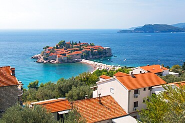 View over rooftops to Budva Bay and the exclusive island resort of Sveti Stefan, Budva, Montenegro, Europe