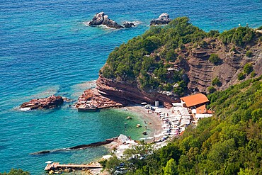 View from clifftop over sheltered cove of clear turquoise water, Sveti Stefan, Budva, Montenegro, Europe