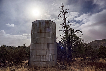 An old water tank perched on a cliff overlooking the T-Bar Ranch Homestead in the Coconino National Forest of Arizona. The ranch is abandoned and owned by the National Forest Service as a historical landmark. No property release needed.