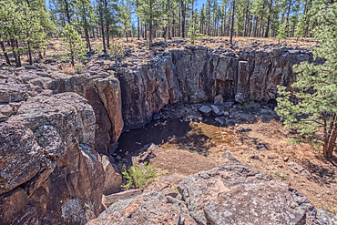 The cliff rim of Keyhole Sink in the Kaibab National Forest near Williams Arizona. This sink is an open ended sinkhole where water can flow out of it.