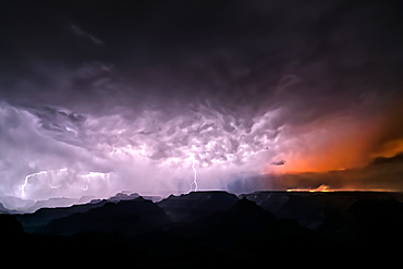 Dragon Bravo wildfire burning on the North Rim of Grand Canyon Arizona with a lightning storm. Viewed from Yavapai Point on the South Rim at night. The fire started from a lightning strike on July 4th, 2025.