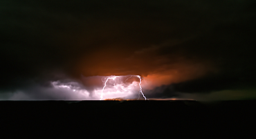Dragon Bravo wildfire burning on the North Rim of Grand Canyon Arizona with a lightning storm. Viewed from Yavapai Point on the South Rim at night. The fire started from a lightning strike on July 4th, 2025.