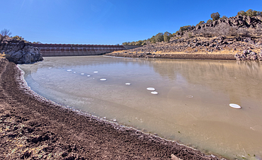 Shoreline view of the historic Bainbridge Steel Dam near Ash Fork Arizona in the Kaibab National Forest. It was originally constructed in the late 1800s and is now a historic landmark that is open to the public.