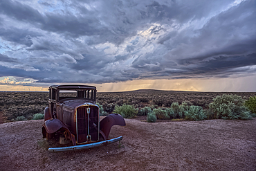 An old Model-T marking historic Route-66 in Petrified Forest National Park Arizona with an approaching storm in the background.