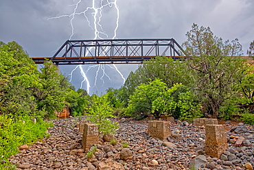 Lightning from a monsoon storm striking behind an old railroad trestle bridge that spans Bear Canyon near Perkinsville, Arizona, United States of America, North America