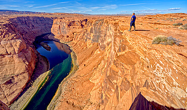 A man hiking on the edge of a cliff overlooking Horseshoe Bend near Page, Arizona, United States of America, North America