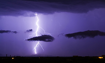 A bright lightning bolt passing through a cloud and striking in the Gila Bend Mountains south of Arlington, Arizona, United States of America, North America