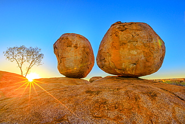 Sunset light rays at Devils Marbles, the Eggs of mythical Rainbow Serpent, at Karlu Karlu (Devils Marbles) Conservation Reserve. Outback, Red Centre, Northern Territory, Australia, Pacific