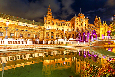 Renaissance building in Plaza de Espana (Spain Square), reflects on channel of Guadalquivir River, illuminated at night, Seville, Andalusia, Spain, Europe