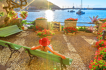 Elegant woman in red with hat at Marciana Marina waterfront, the flowery old district called Borgo al Cotone, Elba island, Tuscan Archipelago, Tuscany, Italy, Europe