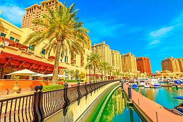 Marina corniche promenade in Porto Arabia at the Pearl-Qatar, with residential towers and luxury boats and yachts in Persian Gulf, Doha, Qatar, Middle East