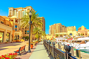 Marina corniche promenade in Porto Arabia at the Pearl-Qatar, with residential towers and luxury boats and yachts in Persian Gulf, Doha, Qatar, Middle East