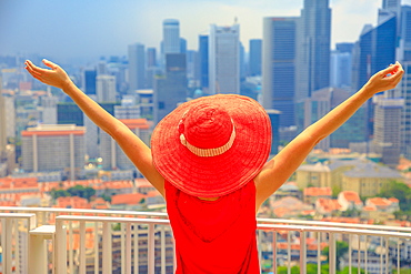 A woman enjoys panorama of Singapore's tallest skyscraper in Chinatown, and view of Sentosa Island and Keppel Harbour, Singapore, Southeast Asia, Asia