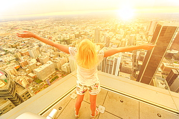 Blonde tourist woman looking at Downtown area of Los Angeles cityscape from observation deck at sunset, Los Angeles, California, United States of America, North America