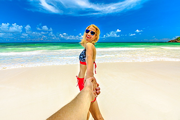 Happy tourist woman in bikini holding hand of her partner, Wild Anse Kerlan, Praslin, Seychelles, Indian Ocean, Africa