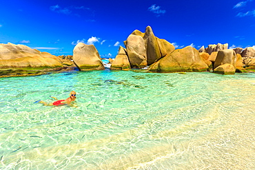 Attractive woman in bikini, in crystal water of natural swimming pool at secret beach, Anse Marron, La Digue, Seychelles, Indian Ocean, Africa