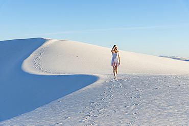 A woman walking along the S curve of a dune's ridge in White Sands National Park, New Mexico, United States of America, North America