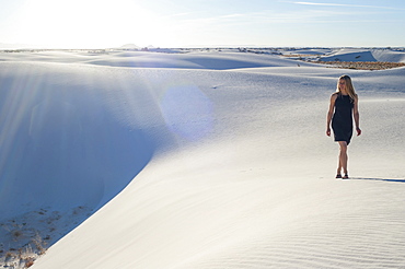 A woman strolls along the ridge of a pure white sand dune in White Sands National Park, New Mexico, United States of America, North America